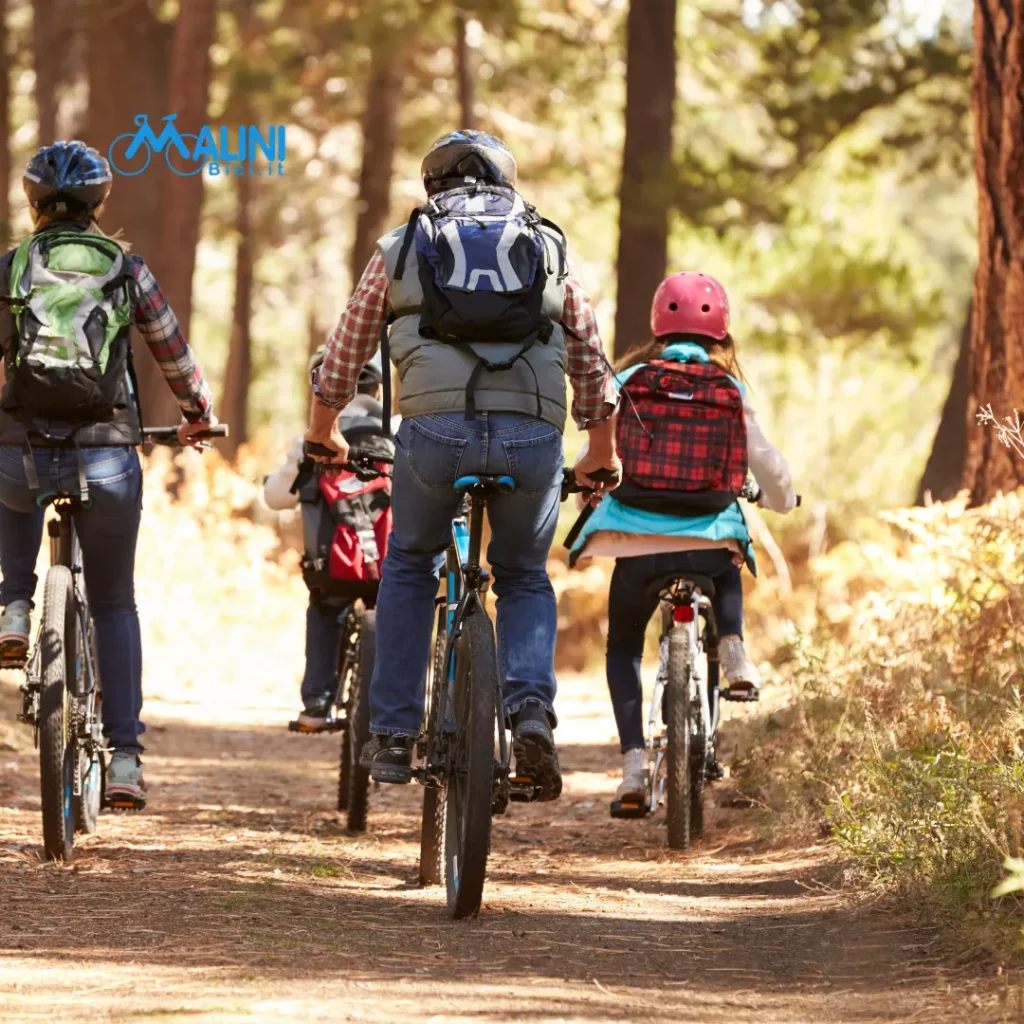 Famiglia in bici su sentiero del Parco Talon a Casalecchio di Reno, gita all’aria aperta con caschi e zaini